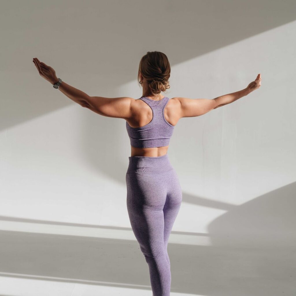 Woman dressed in lilac workout wear arms wide open